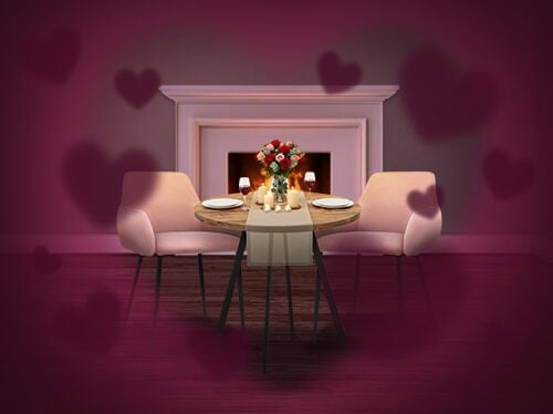 Romantic dining setup with a small round table set for two, pink upholstered chairs, candles and a bouquet of roses, placed in front of a lit fireplace, with soft heart-shaped overlays creating a Valentine&rsquo;s Day atmosphere. Click to see the items in promotion