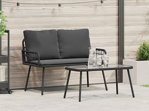 A 2-seater rattan garden sofa paired with a glass-top table, set in a cozy garden space.