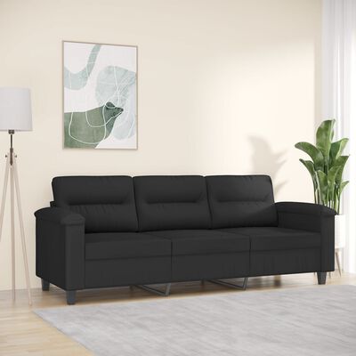 Black three-seat sofa in a bright living room setting with plant and wall art