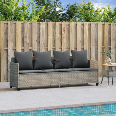 Outdoor loveseat with gray cushions and side table beside, by a wooden fence and pool edge.