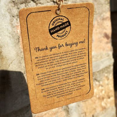 Tag attached to a wooden product reading handmade, original, thank you for buying me, with small text on tag.