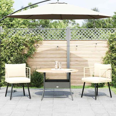 Round-topped table with two cream cushioned chairs and a large beige umbrella overhead.