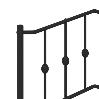 Close-up of a black metal bed frame corner showing vertical spindles with decorative beads and the top rail.