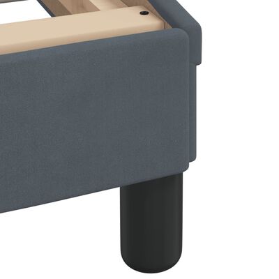 Close-up of dark blue fabric upholstery on the bed’s side panel and rounded leg.