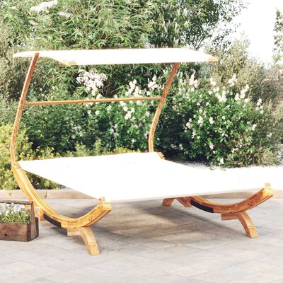 A wooden canopy bed/sofa hybrid with curved supports and a white mattress, displayed outdoors on a patio.