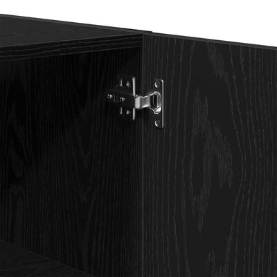 Close-up of a metal hinge on the interior of a black cabinet.