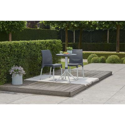 Outdoor patio with two chairs and a small round table on a rug.