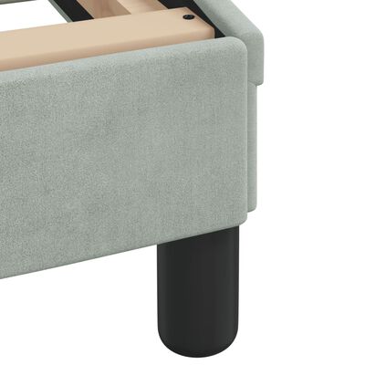 Corner detail of bed frame showing upholstered side panel and black rounded leg.