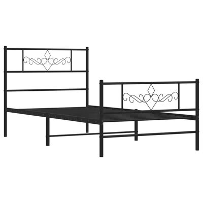 Two black metal beds, one larger frame behind the other, both with decorative scrollwork on headboard and footboard