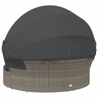 Round wicker outdoor daybed with dark protective cover over cushions