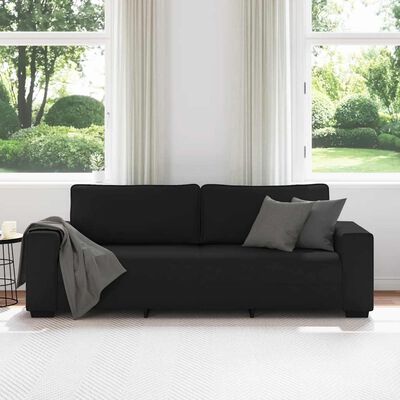 Black fabric sofa with two back cushions in front of a window with white curtains.