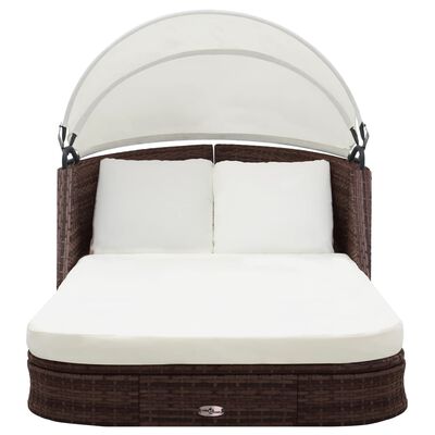 Brown wicker outdoor daybed with white cushions and canopy