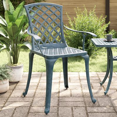 Single lattice-back patio chair with armrests placed outdoors next to a small table.