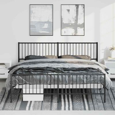 Black metal bed frame with double headboard in a minimalist bedroom, two pictures above bed, gray bedding.