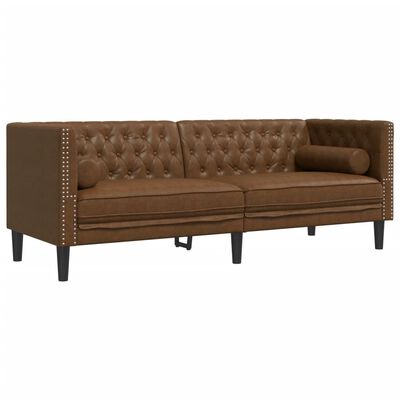Close-up of brown tufted sofa with studded seams on arms and a bolster pillow.