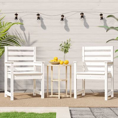 Two white wooden chairs with slatted backs facing a small table with lemons, set against a white wall with string lights.