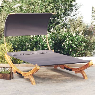 A chaise-daybed with dark gray fabric, curved wooden base, and a canopy-like shade; cushions along the back edge.