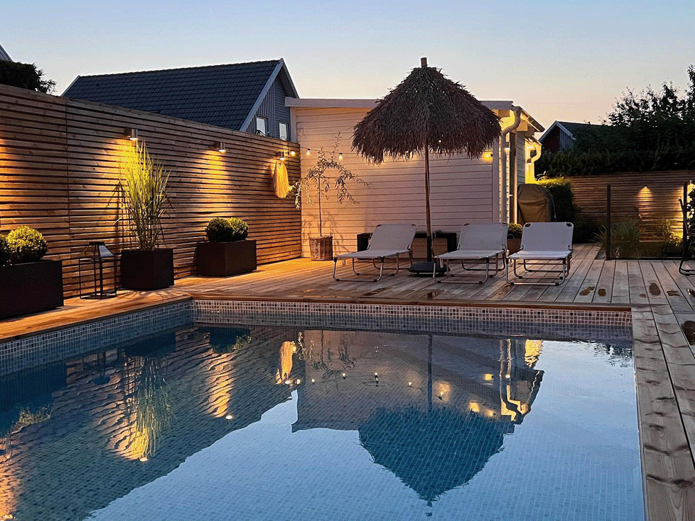 Backyard pool area with fence and wall light fixtures