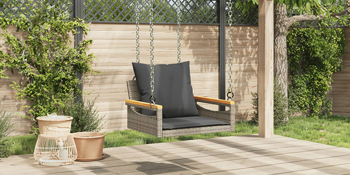 Rattan outdoor swing bench with dark cushions on a patio. Click to shop the collection.